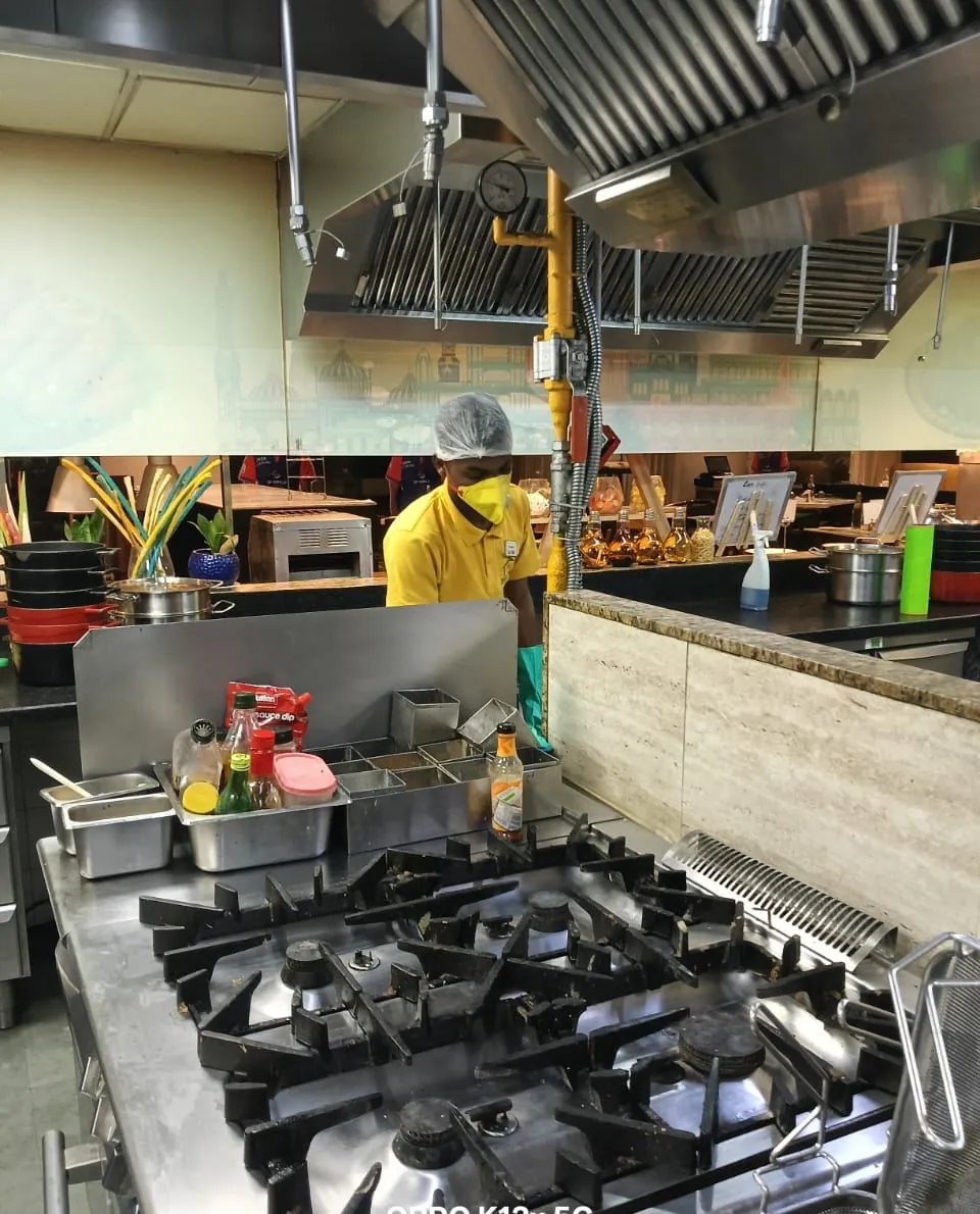 Safe Home technician applying gel bait under the cooking range in a hotel kitchen